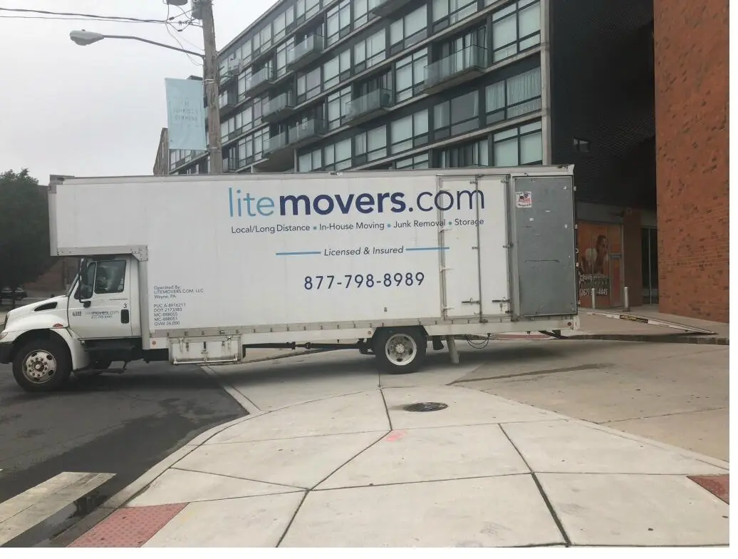LiteMovers box truck at a mid-rise apartment building on a city street